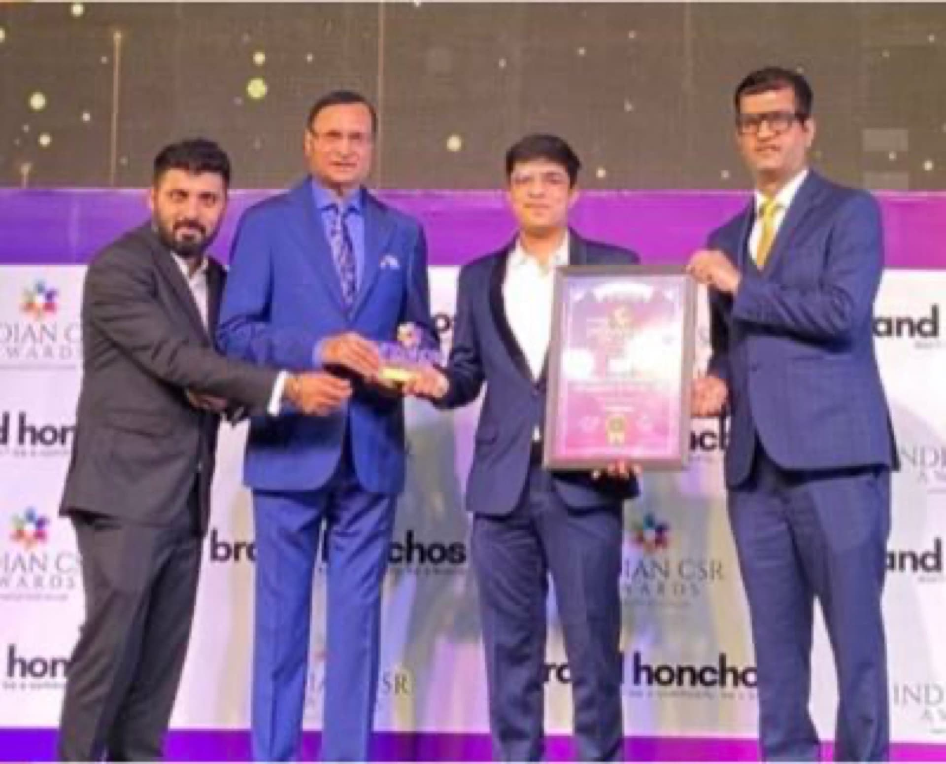 Pledge A Smile receiving a trophy on stage at the Indian CSR Awards
