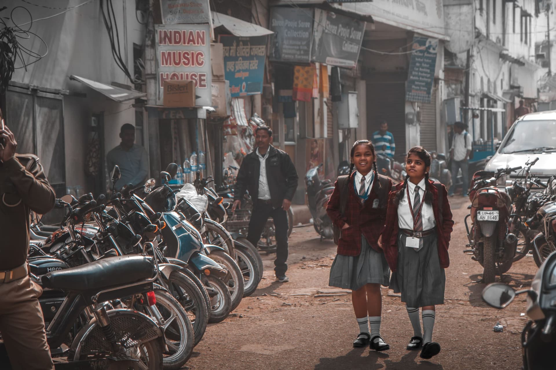 Two schoolgirls in uniform walking along a busy street in Amritsar, Punjab, India
