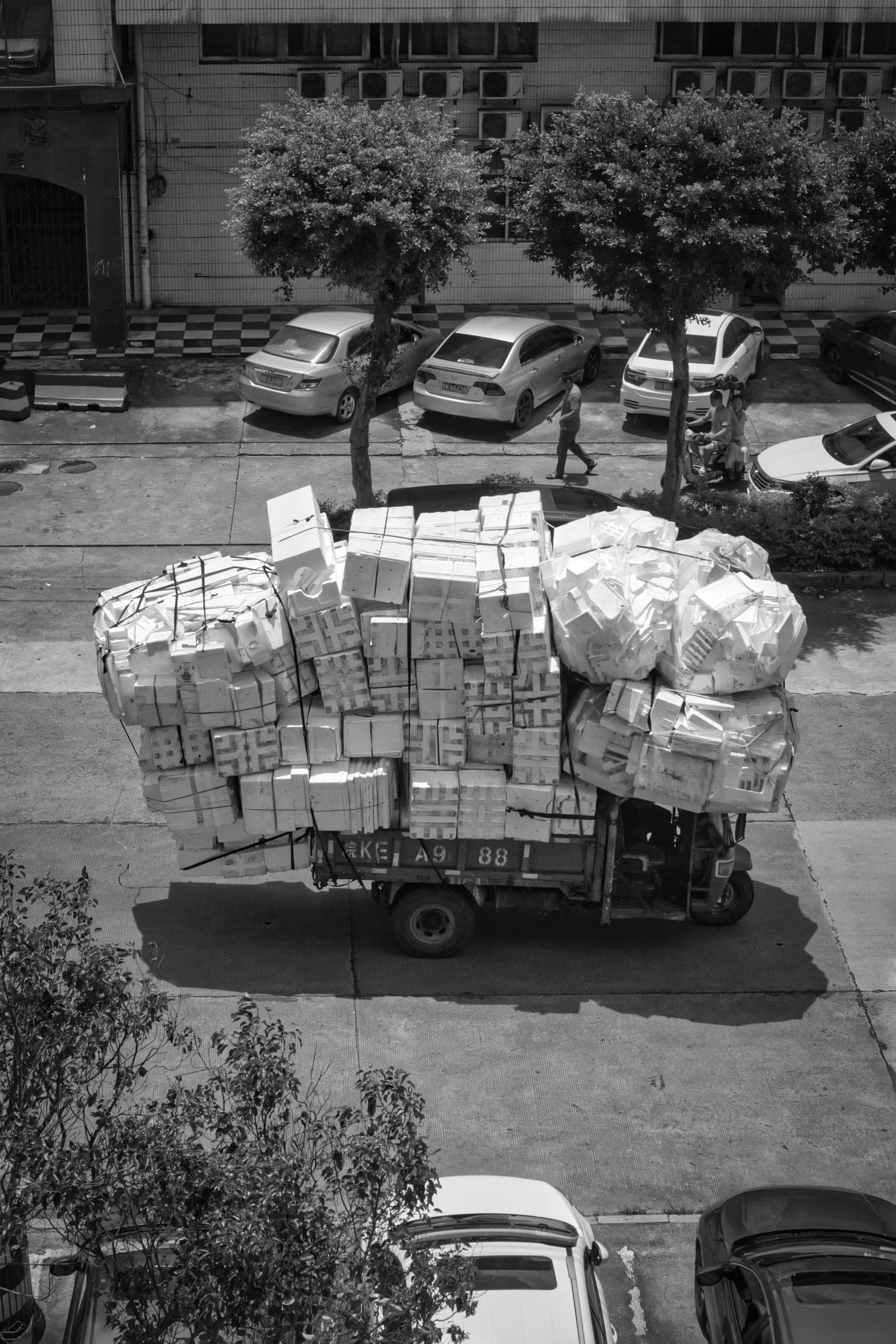 High angle view of a truck heavily loaded with stacked boxes on its cargo bed, driving through a city street