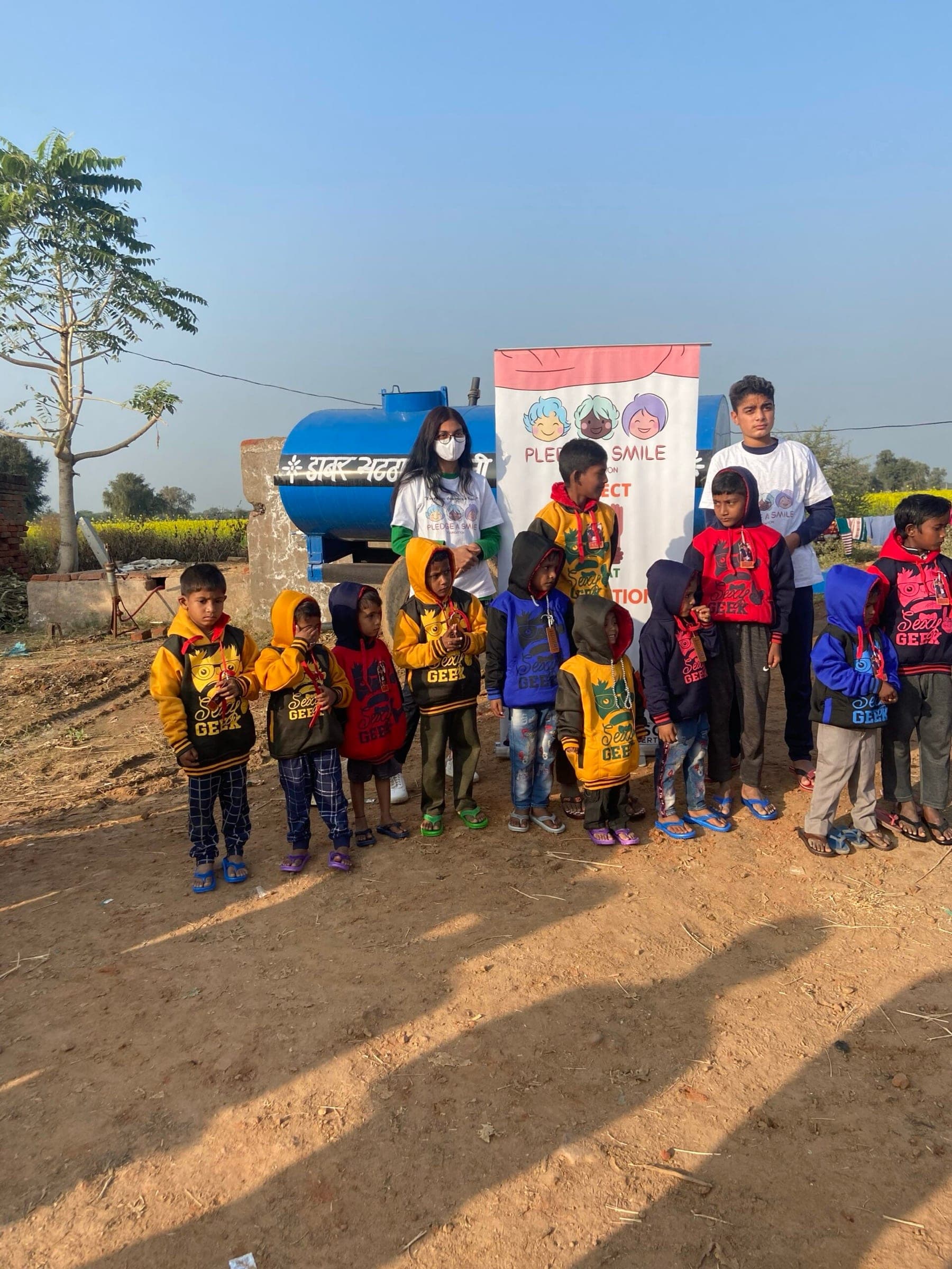 Wide lineup of kids and volunteers with mustard fields behind — scene-setting context