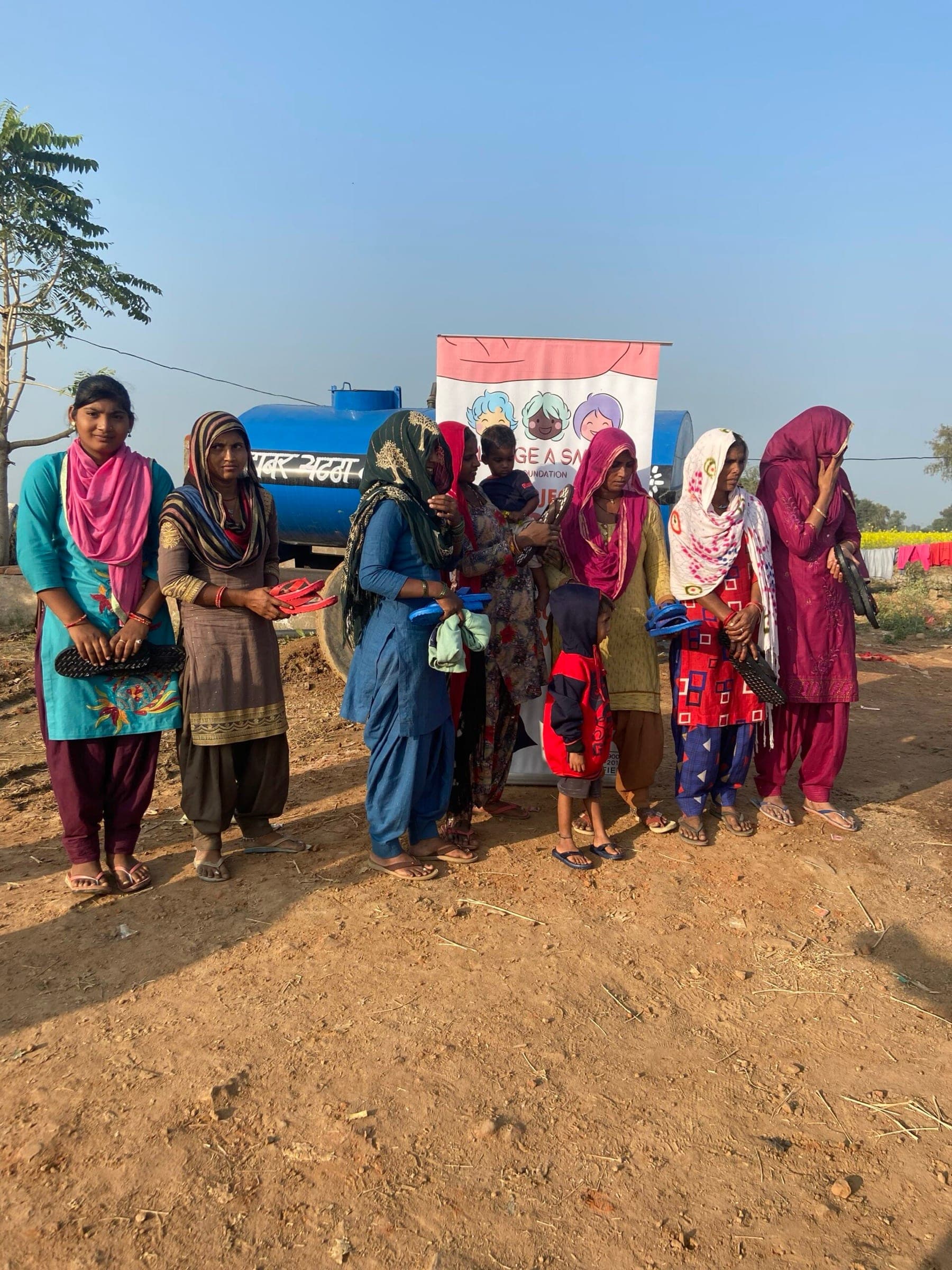 Row of women holding their new footwear, colourful dupattas, warm morning light — faces and colour