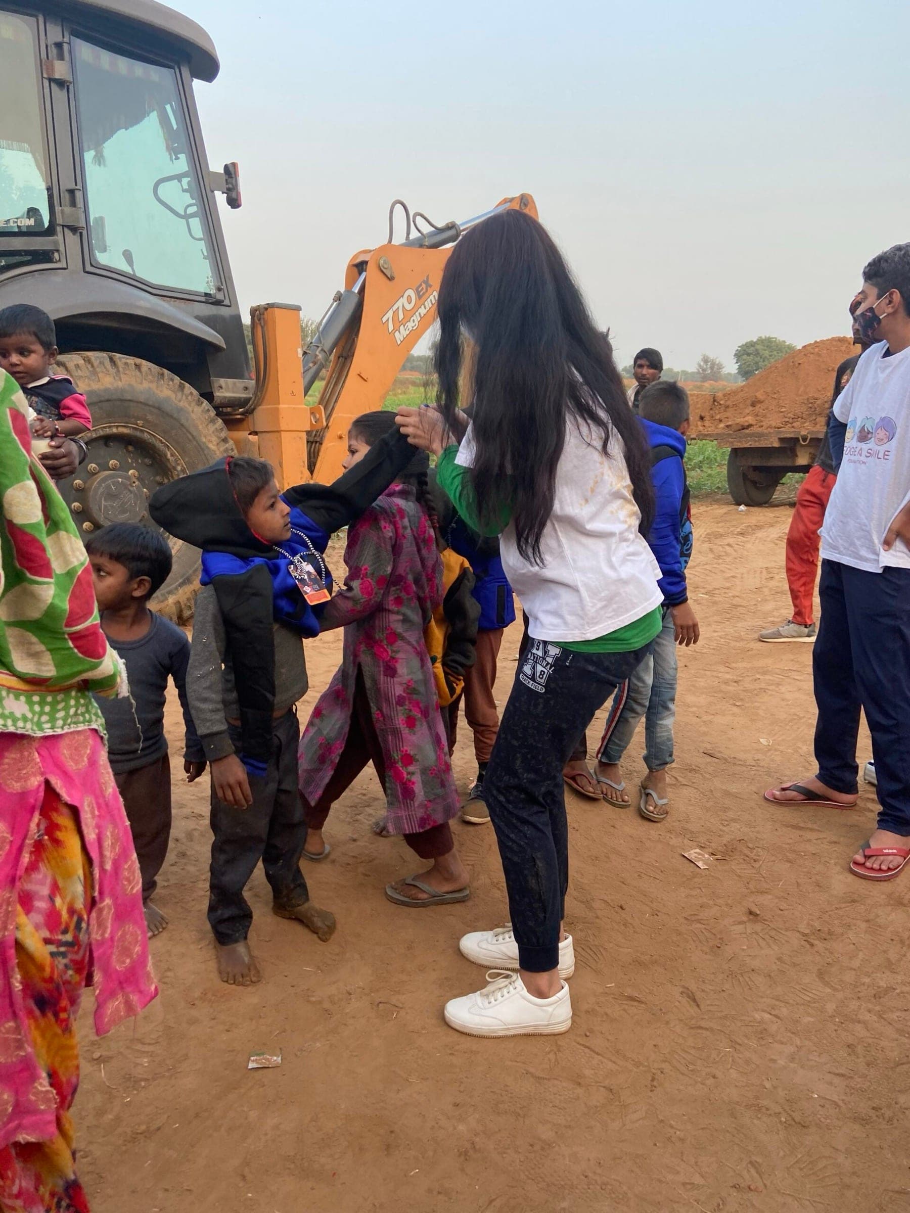 Volunteer helping a small child pull on a new hoodie — the most candid working moment in the set