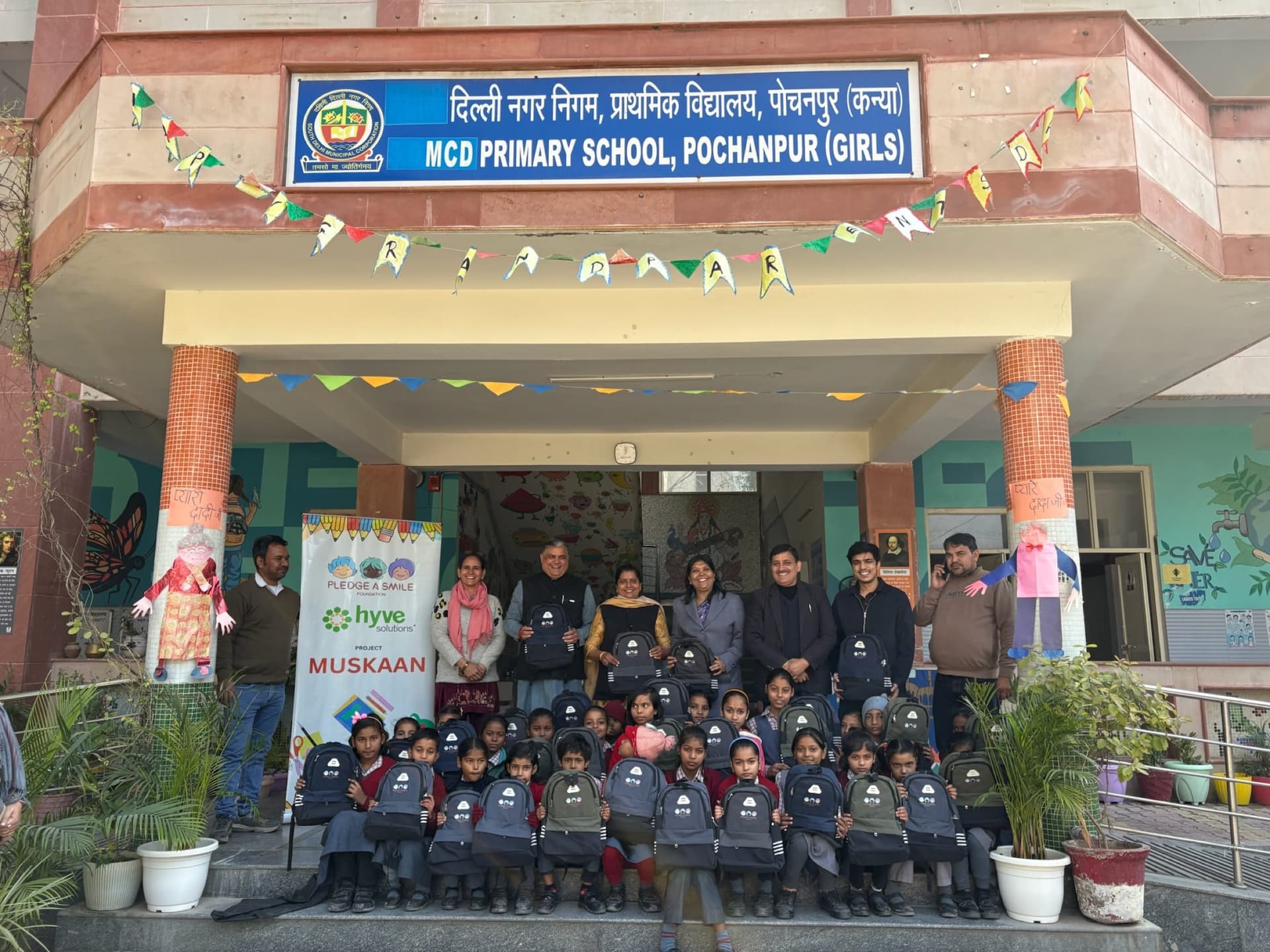Girls' school entrance with festival decorations, kids and teachers with kits - wide scene