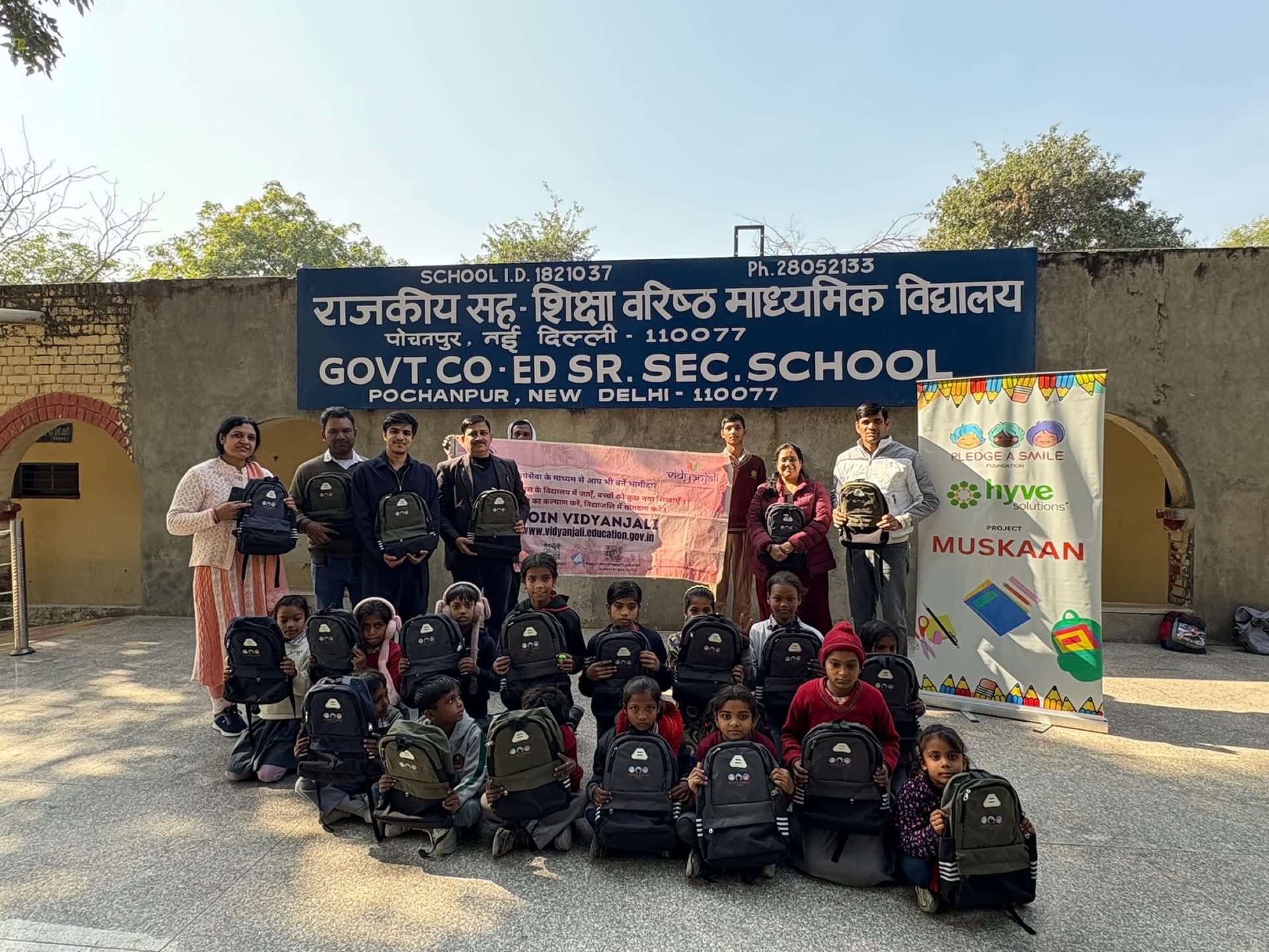 Govt Co-Ed Sr Sec School signboard above kids with new backpacks - strong location context