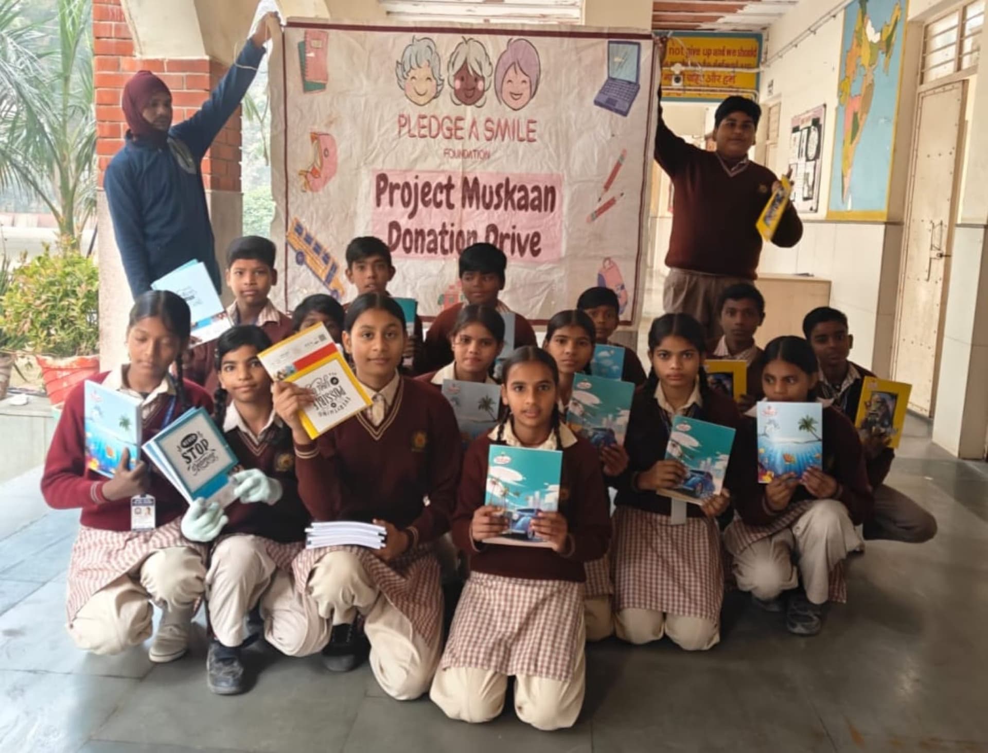 Indoor corridor group under Pledge A Smile banner with fresh notebooks.