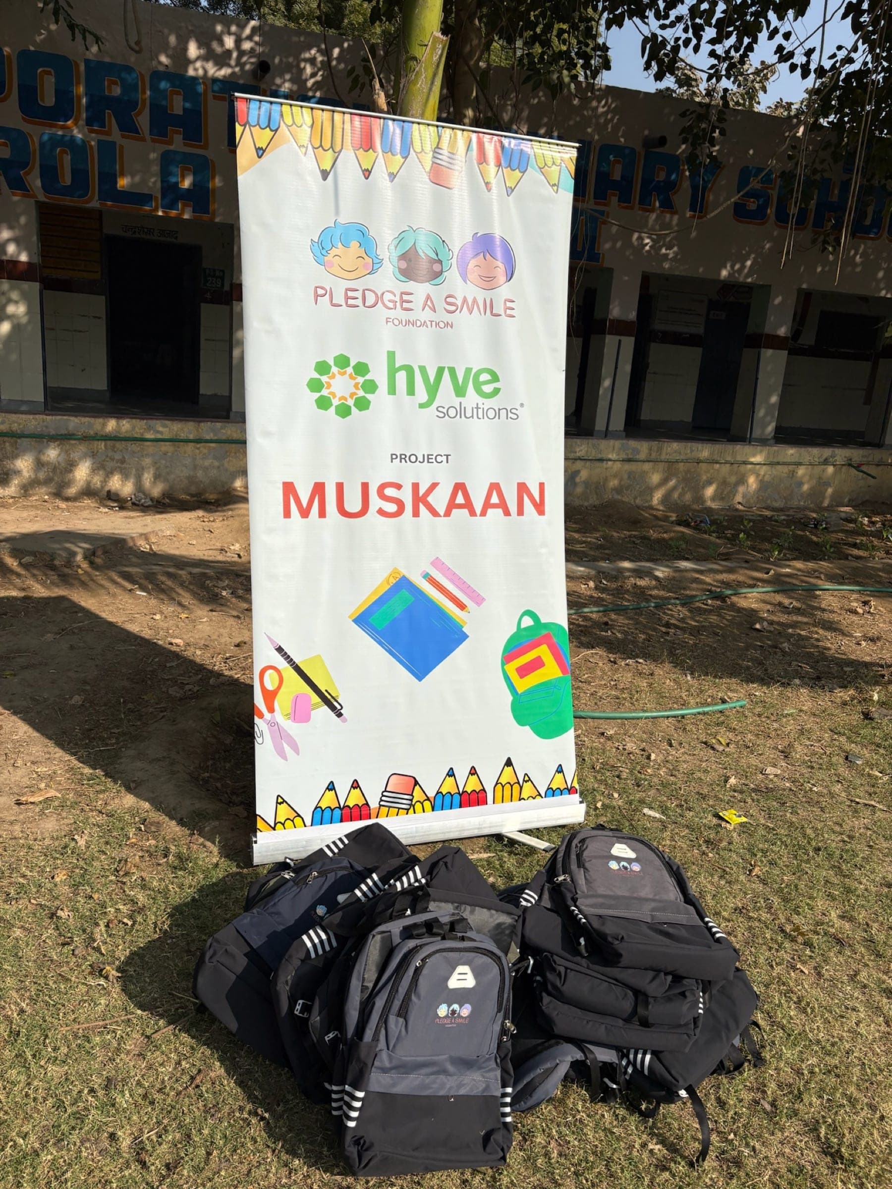 Project Muskaan roll-up banner with stacked backpacks - clean branding detail shot