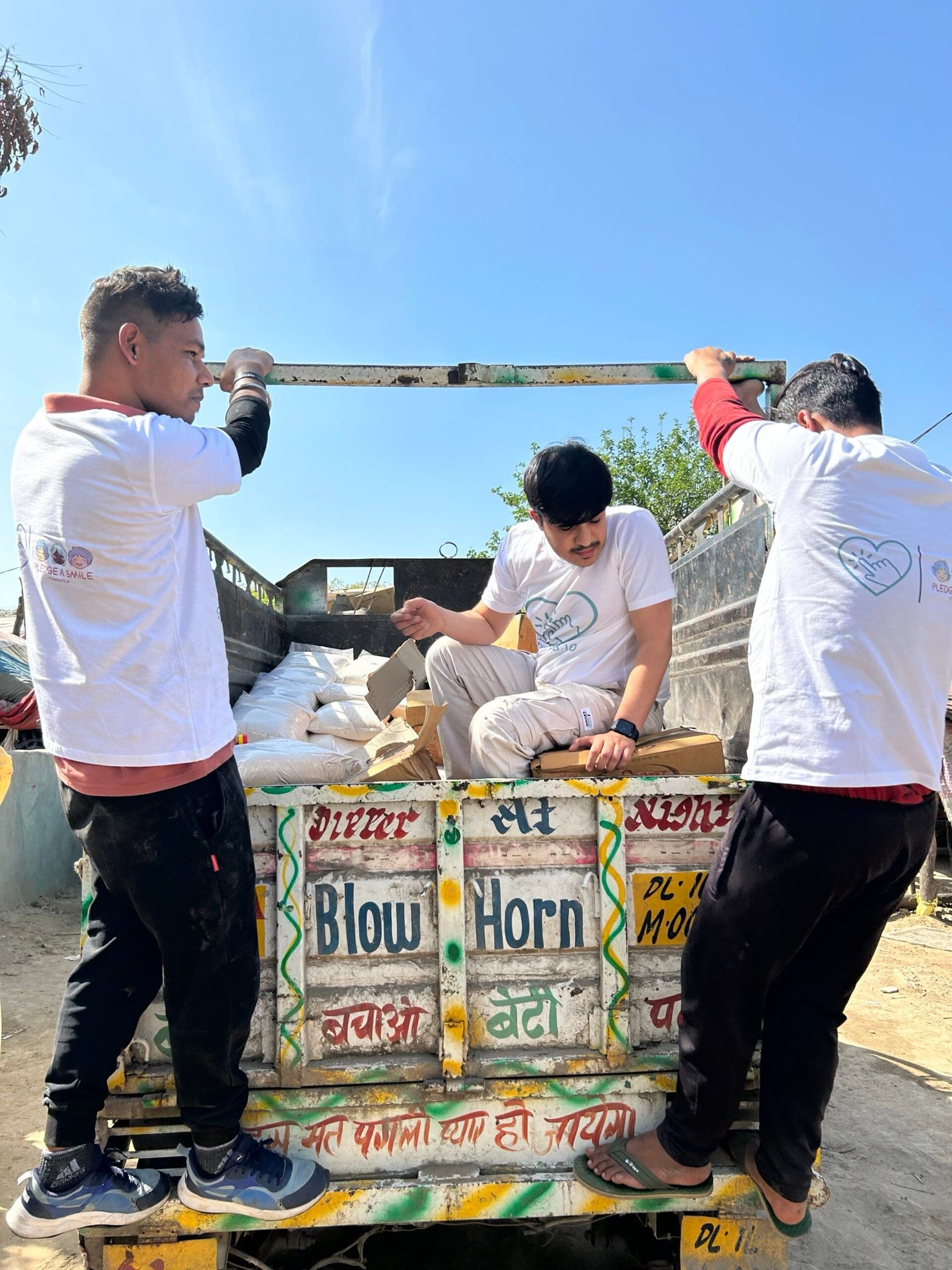 Behind-the-scenes: volunteers climbing onto a painted truck to unload ration sacks