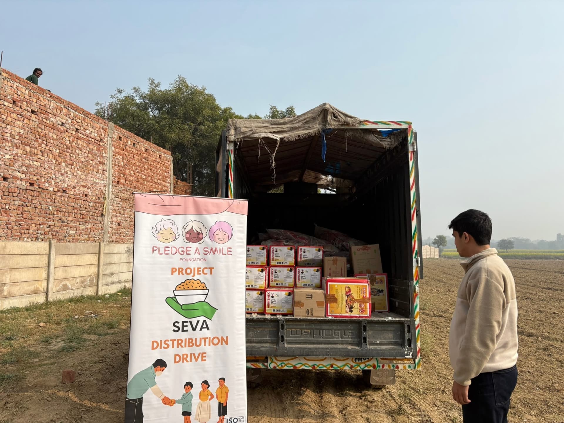 Logistics detail: truck bed stacked with ration kit boxes beside the SEVA banner