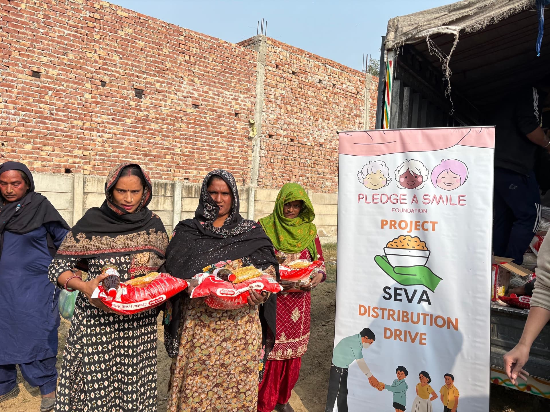 Volunteer handing atta bag to woman, SEVA banner clearly visible