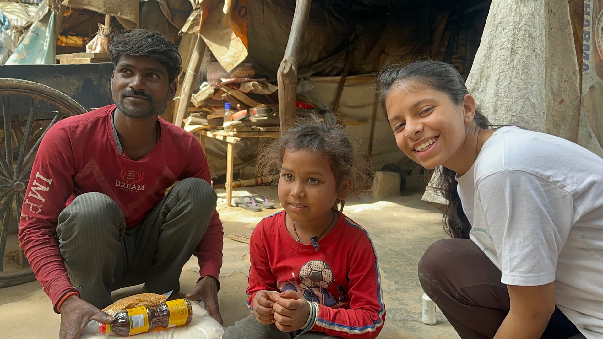 A man, a young girl and a Pledge A Smile volunteer share a genuine smile mid-handover — the warmest exchange of the drive.
