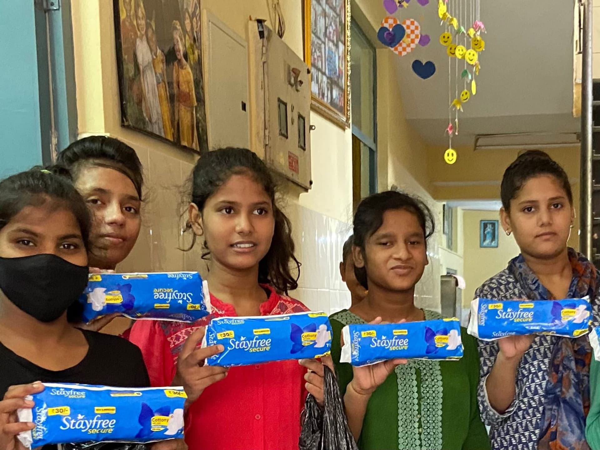 Noori: medium group of girls holding Stayfree packs, expressive faces