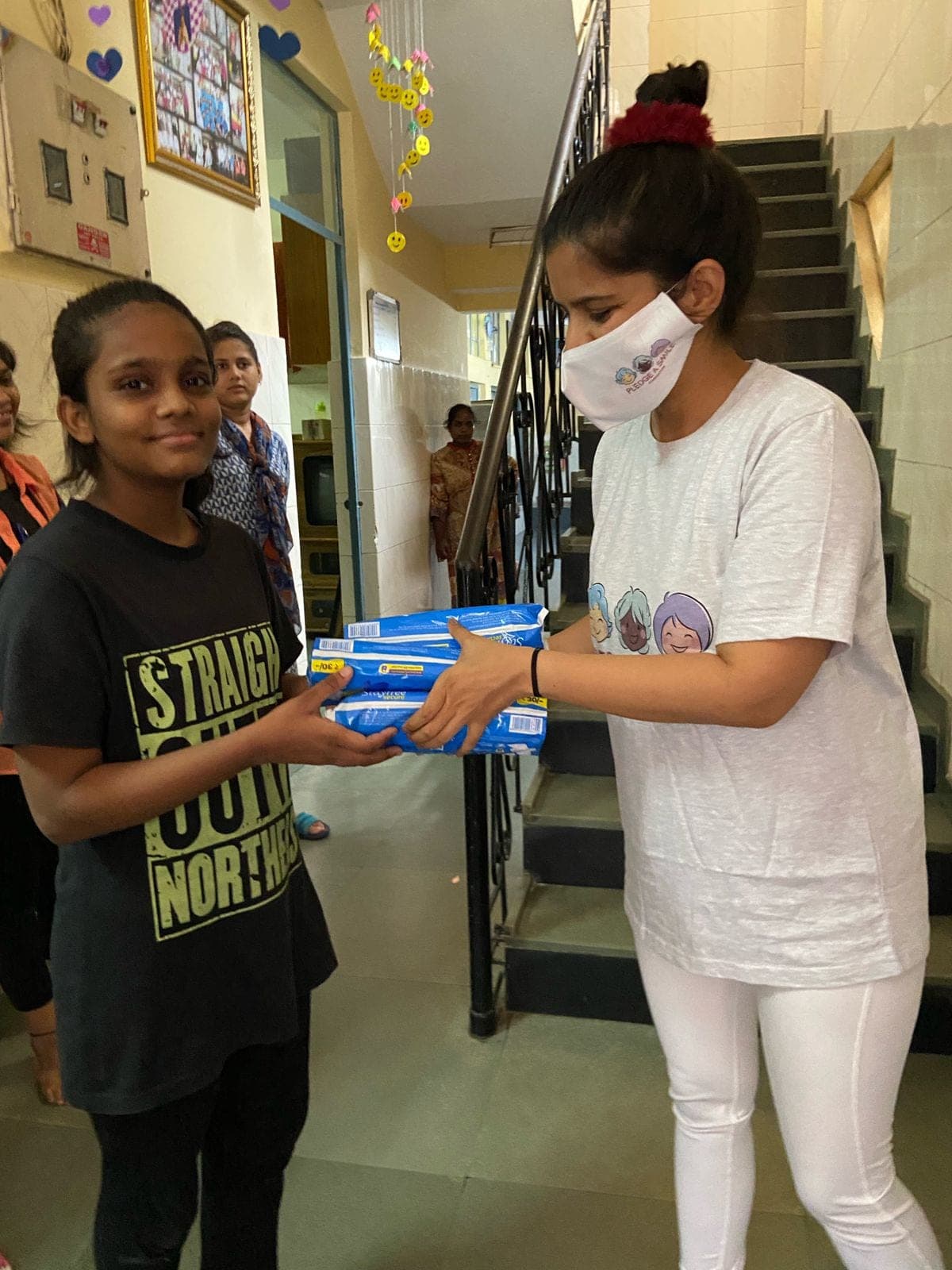 A one-on-one Noori handover to a girl in a graphic tee.