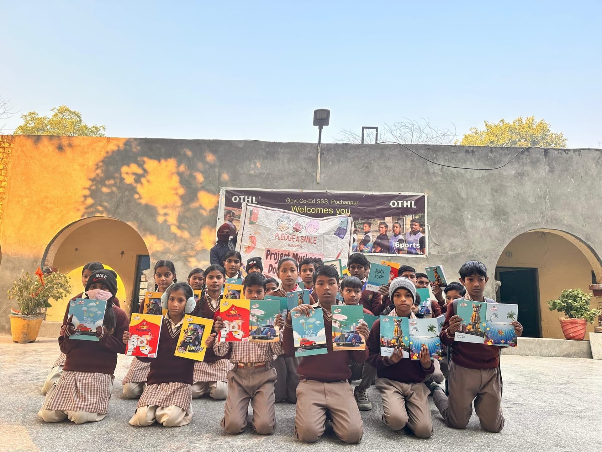 Children holding up new notebooks in golden courtyard light