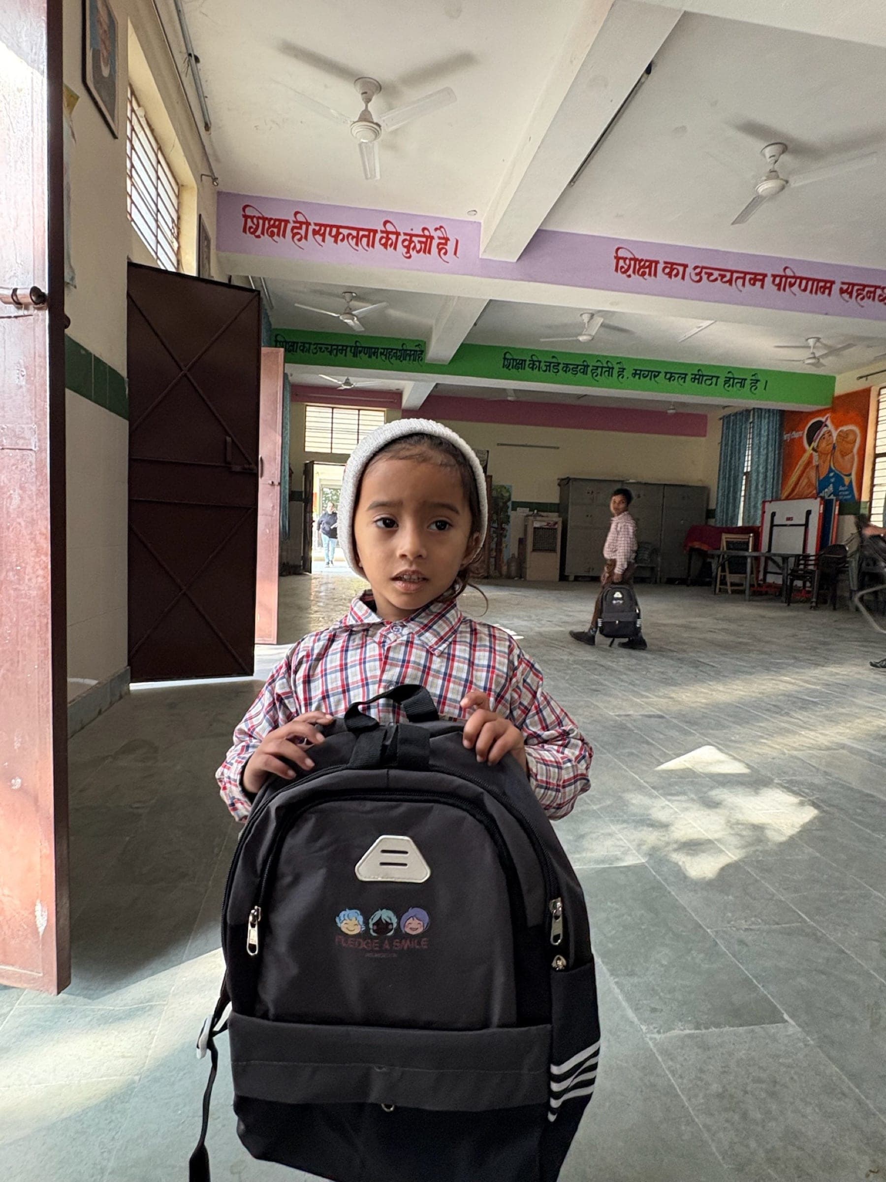 Small girl in a white knit cap presenting her new backpack