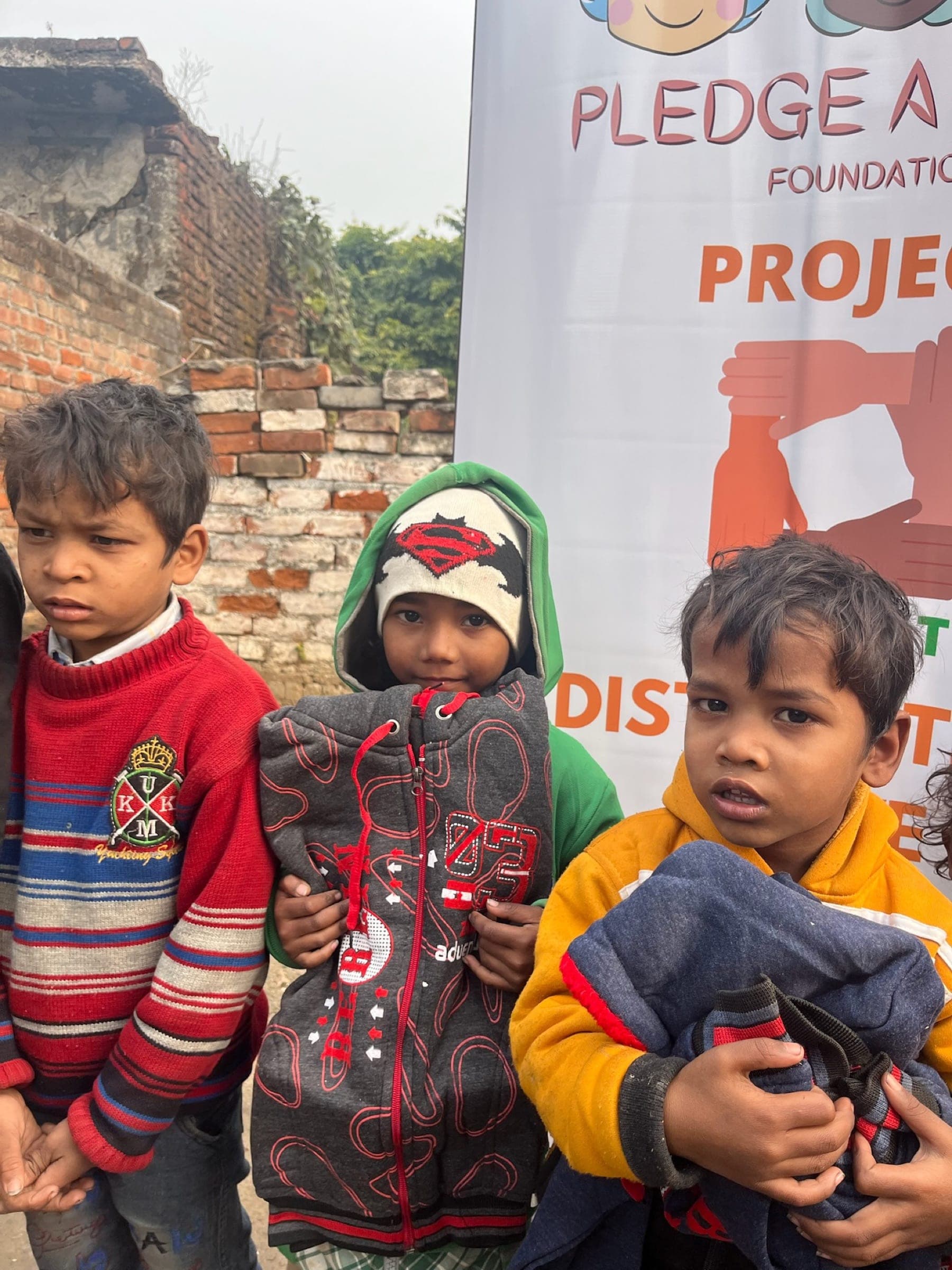 Three young boys clutching their new winter jackets