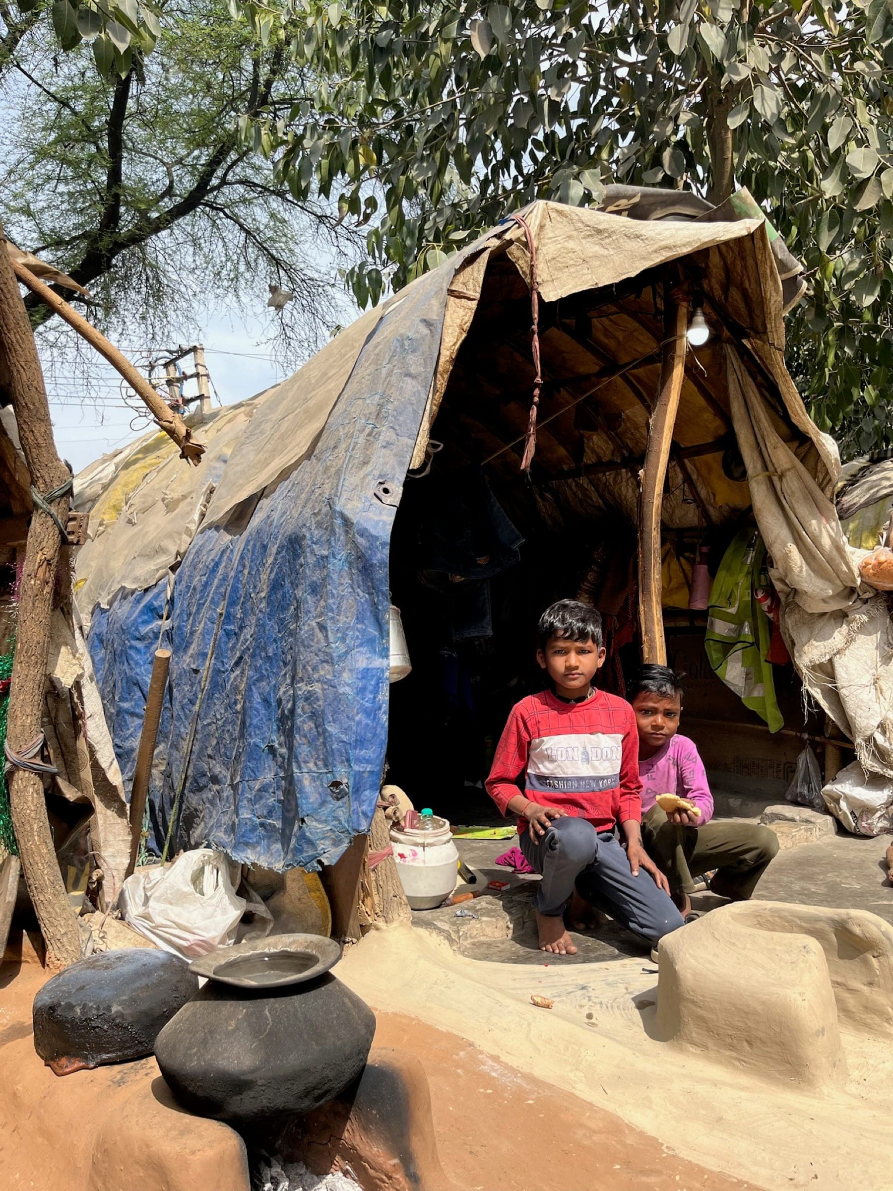 Environmental documentary: two boys at their tarpaulin tent home — context of the communities served, no branding