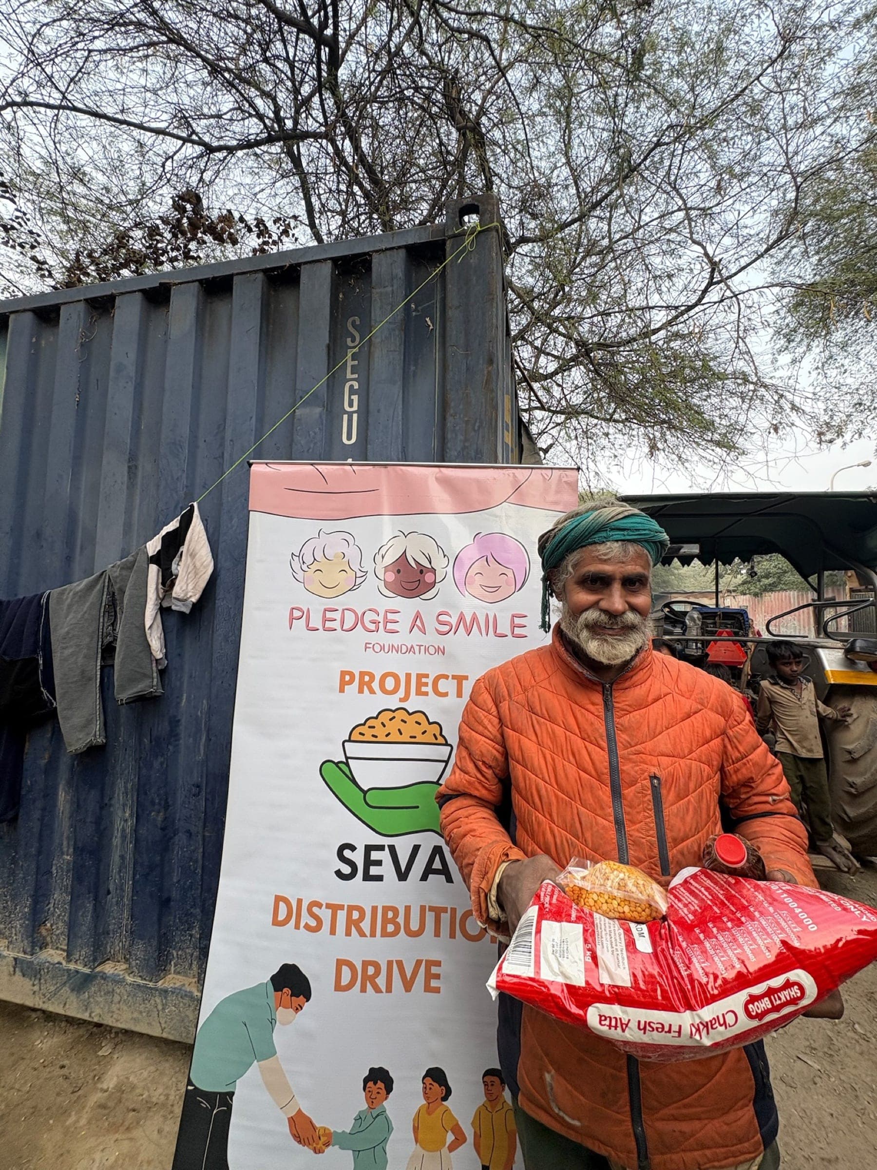 Elderly man in an orange jacket and green turban with his ration kit